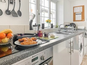 Een keuken met een fornuis, spoelbak en een raam met uitzicht.