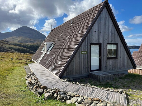 Une cabane en bois avec un toit en pente, une porte et une fenêtre.