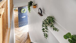 A staircase with a wooden handrail, a white wall, and a blue door at the bottom. - 4 bedroom accommodation in Little Dunham (Little Dunham)