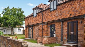 A brick building with a front door, a small porch, and a window. - 4 bedroom accommodation in Little Dunham (Little Dunham)