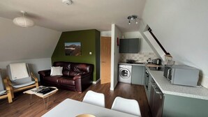 Un espace de vie compact comprenant un coin repas, un canapé, un lave-linge et une kitchenette.