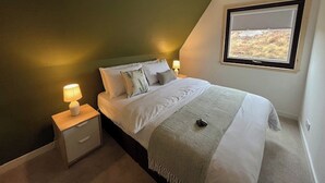 Une chambre à coucher avec un lit, des lampes de chevet, une fenêtre et un luminaire suspendu.