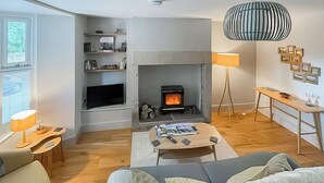A modern living room with a fireplace, wooden flooring, a sofa, a coffee table, and a lamp. - 2 bedroom accommodation in Crook, near Bishop Auckland (Crook, near Bishop Auckland)
