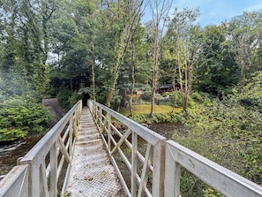 A wooden bridge leading to a cabin surrounded by dense forest.