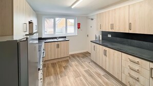 A modern kitchen with wooden cabinets, a black countertop, and a window providing natural light.