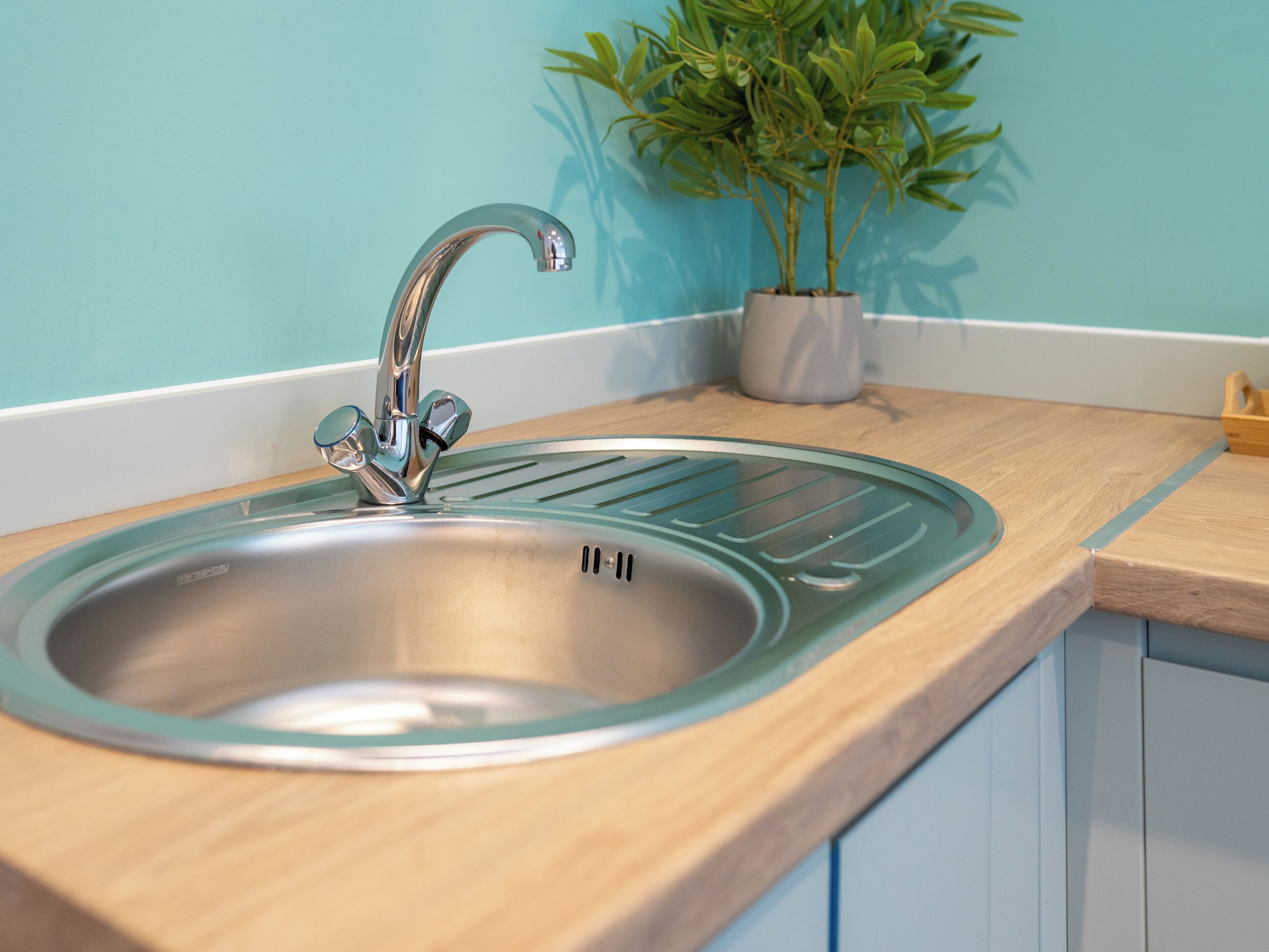 Ein Küchenspülbecken mit modernem Wasserhahn, ein Topfpflanze und Holz Arbeitsplatten.