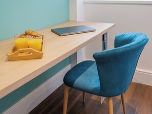 A modern kitchen with a wooden countertop, a laptop, and a blue chair.
