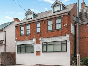 A two-story brick building with a sign for Hilltop Serviced Apartments on the ground floor.