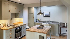 Une cuisine moderne avec des meubles gris, un plan de travail en bois et un îlot central.