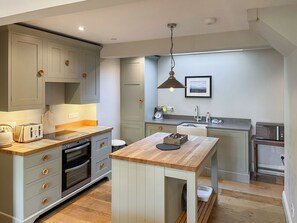 A modern kitchen with grey cabinets, a wooden countertop, and a central island.