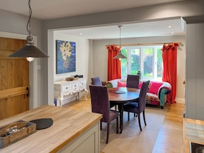 A dining area with a wooden table and chairs, a white cabinet with drawers, and a painting on the wall.