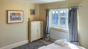 A bedroom with a bed, a wardrobe, a radiator, a window with curtains, and two framed pictures on the wall. - 3 bedroom accommodation in Ampleforth, near Helmsley (Ampleforth, near Helmsley)