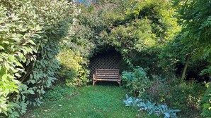 A garden with a wooden bench surrounded by dense foliage and a lattice fence. - 3 bedroom accommodation in Ampleforth, near Helmsley (Ampleforth, near Helmsley)