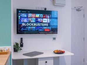 A flat-screen TV mounted on a white wall displaying a streaming service interface with the word "BLOCKBUSTERS" prominently.