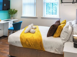 A neatly arranged bedroom with a bed, a desk, and a chair.