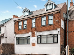 A two-story building with a sign for Hilltop Serviced Apartments at 122 High Street - Earl Shilton.