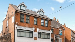 A two-story brick building with multiple windows and a sign for Hilltop Serviced Apartments. - Hilltop Apartment 7 - UK50599 (Earl Shilton)