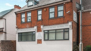 A two-story brick building with a sign indicating '122 High Street - Earl Shilton' and 'Hilltop Serviced Apartments'.
