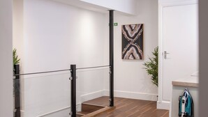A modern interior with a wooden floor, a glass railing, and a painting on the wall.