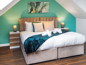 Un dormitorio moderno con una cama grande, paredes color aguamarina y suelo de madera.