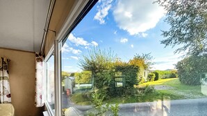 A room with a large window offering a view of a rural landscape, including a road, greenery, and a small building. - 2 bedroom accommodation in Machynlleth (Machynlleth)