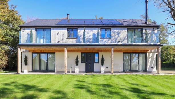 A modern two-story house with a covered front porch, large windows, and solar panels on the roof. - 4 bedroom accommodation in Royal Wootton Bassett (Royal Wootton Bassett)