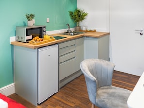 Una cocina compacta con microondas, lavabo y refrigerador pequeño.
