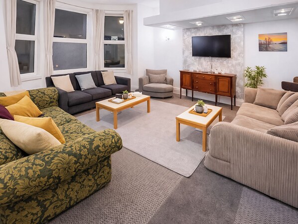 Una sala de estar con sofá, sillón, mesa de centro, televisor y aparador.