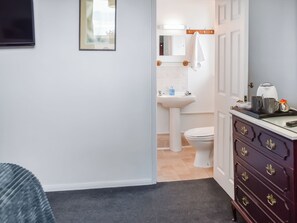 Ein Badezimmer mit Waschbecken, Toilette und Spiegel. Über dem Waschbecken befindet sich ein Handtuchhalter und darunter ein Schrank mit Schubladen.