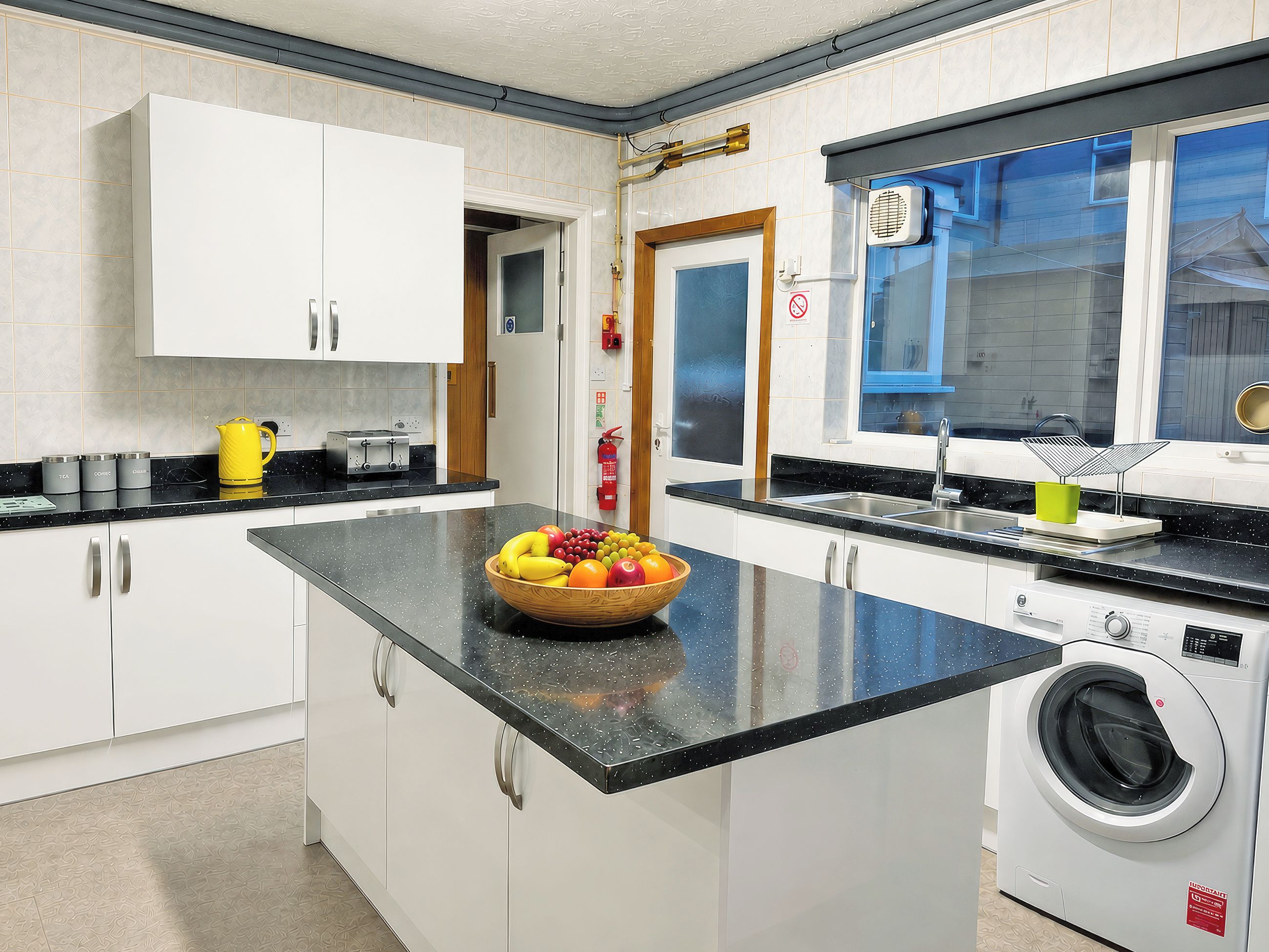 A kitchen with a central island, a washing machine, and a window with a view.