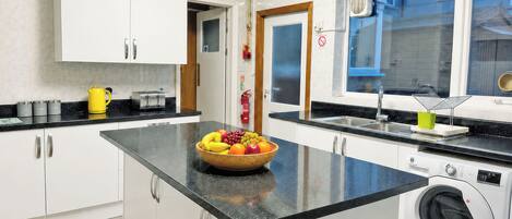 A kitchen with a central island, a washing machine, and a window with a view.