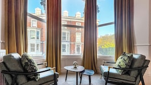 A room with two leather armchairs, a small round table, and a view of a building with a sign reading "SELBORNE HOTEL".