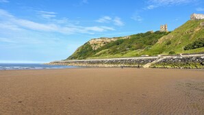 A beach with a stone wall and a castle on a hill.