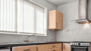 Eine Küche mit Holzausstattung, einem Einbauofen und einem Fenster mit Jalousien.