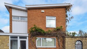 Ein zweistöckiges Ziegelhaus mit weißer Haustür, einer Garage und einem kleinen Fenster.