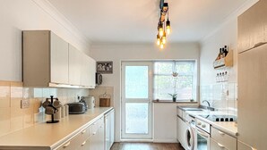A modern kitchen with a central island, built-in appliances, and a window with blinds. - 2 bedroom accommodation in Redcar (Redcar)