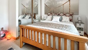 A bedroom with a wooden bed, a large mirror, and a hammock-style headboard. - 2 bedroom accommodation in Redcar (Redcar)
