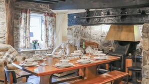 Un comedor rústico con paredes de piedra, mobiliario de madera y una chimenea.