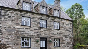 Un edificio de piedra con varias ventanas, una puerta y mesas al aire libre.