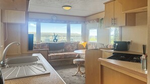 A compact kitchen with a sink, stove, and a window overlooking a scenic landscape.