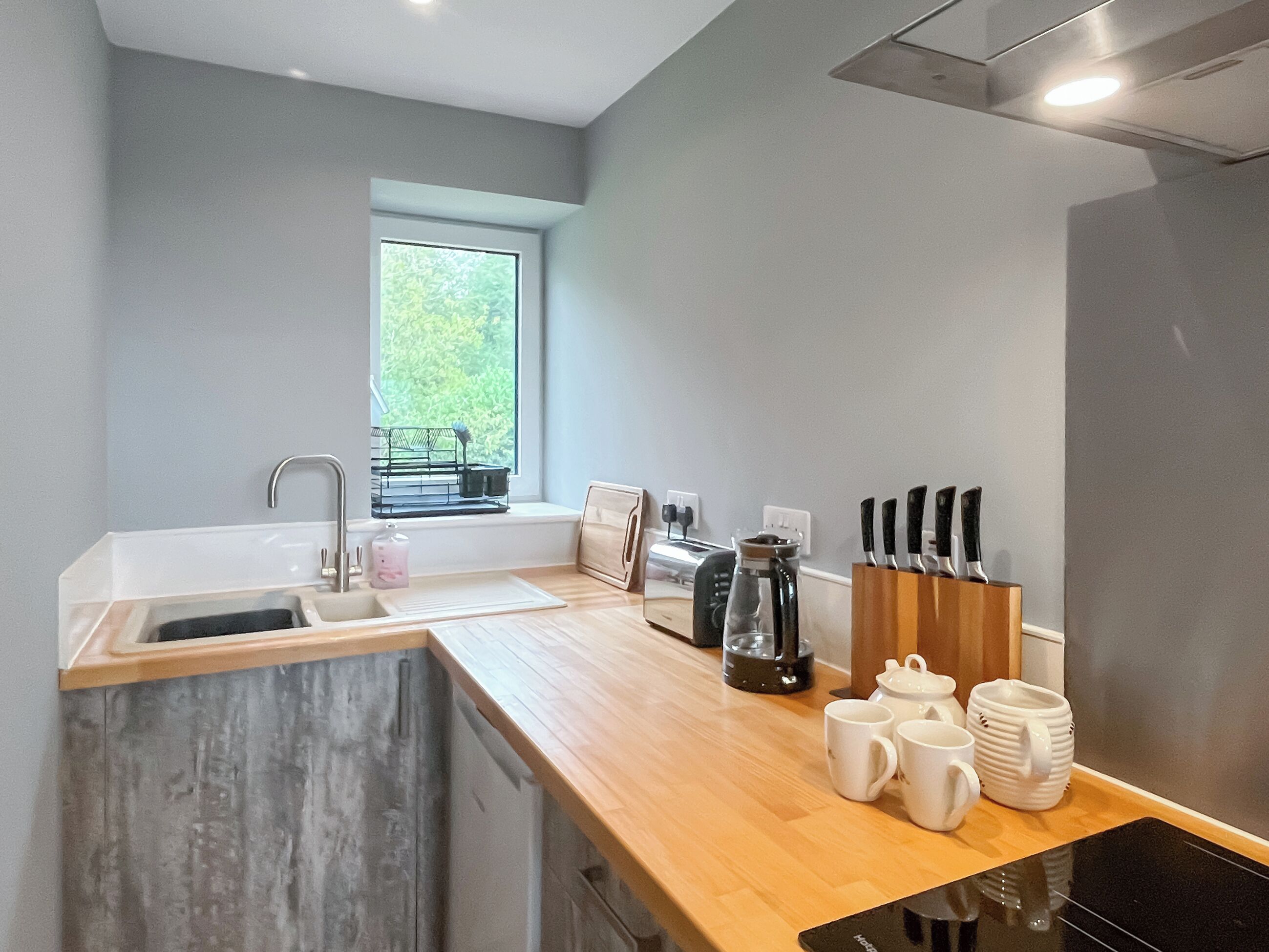 Eine moderne Küche mit Holzarbeitsplatte, Spüle, Fenster und einer Kaffeemaschine.