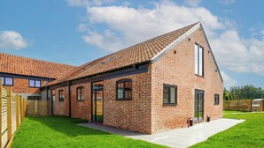 A brick house with a tiled roof, a large window, and a door.