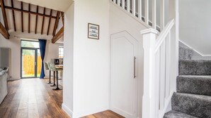 A hallway with wooden flooring, a staircase, and a door with a sign above it.