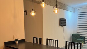Eine moderne Küche mit einer Holztheke, Pendelleuchten und einem grünen Stuhl im Hintergrund.