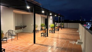 Eine Terrasse im Freien mit Fliesenboden, Blumentöpfen und Gartenmöbeln.
