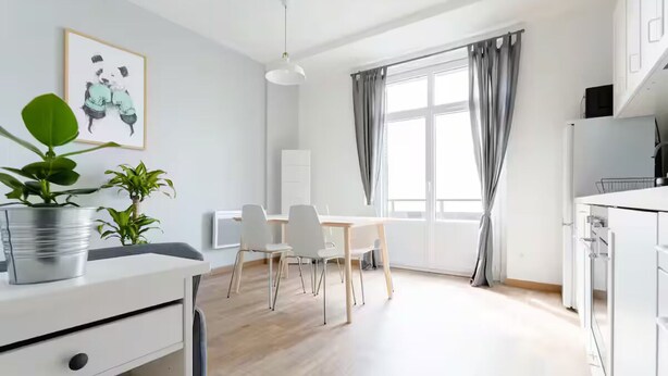 A modern kitchen with white cabinets, a dining area with a table and chairs, and a large window with curtains.