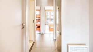 Un couloir avec un lit, un radiateur et une porte donnant sur une pièce.