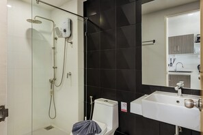 A modern bathroom with a glass-enclosed shower, a white toilet, and a sink with a mirror above it. - Studio in Ozone Condo in Kata A702 (Karon)