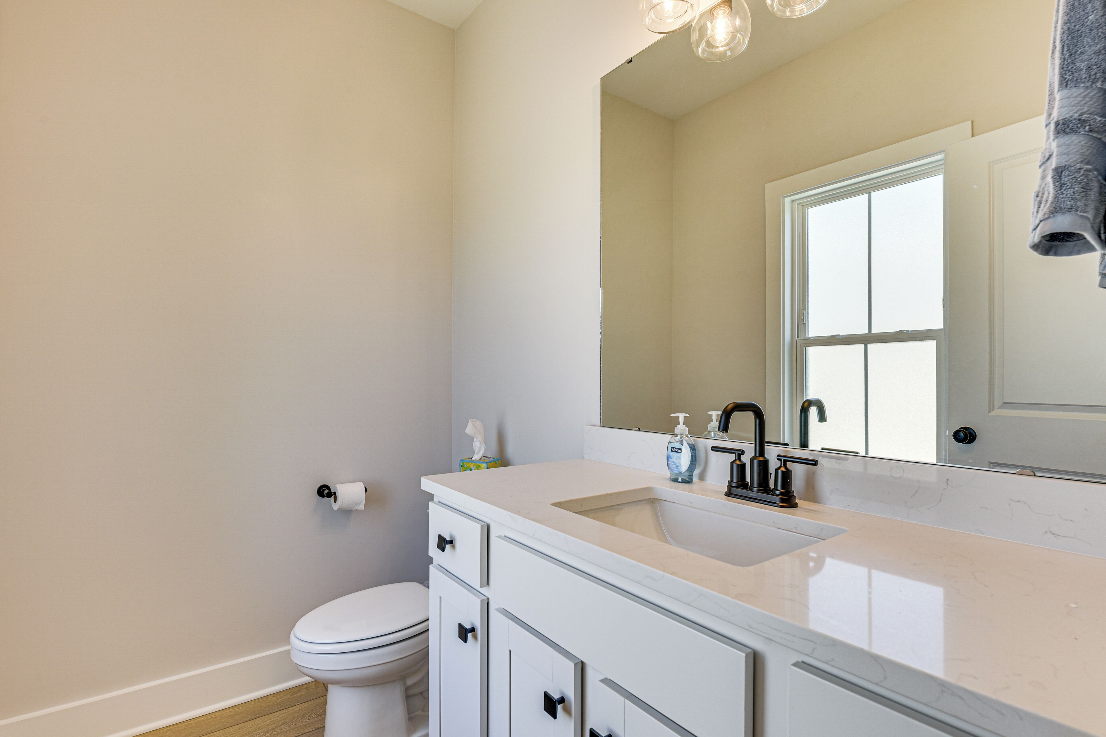 A modern bathroom with a white sink, a mirror, and a toilet.