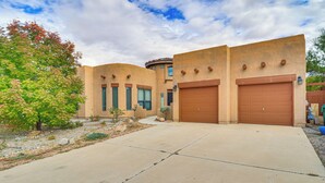 A two-story building with a flat roof, large garage doors, and a paved driveway. - Furnished Rio Rancho Rental w/ Patio & Yard (Rio Rancho)
